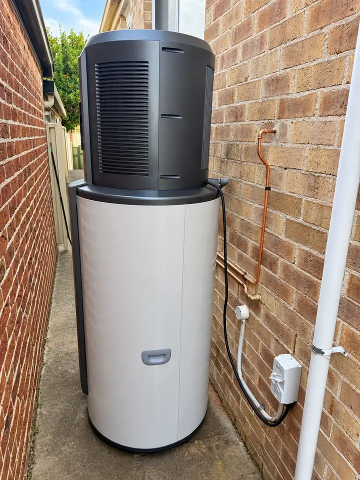 Haier heat pump hot water system installed beside a brick house in NSW under the hot water rebate